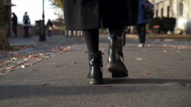 Mujeres pies en botas negras pisando el suelo durante el día soleado — Vídeos de Stock