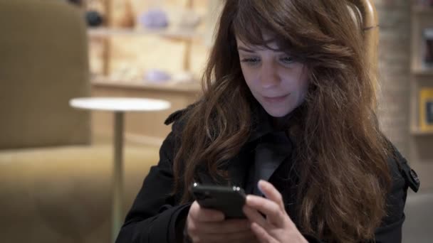 Gros plan de cheveux bruns féminins faisant défiler un téléphone, souriant — Video