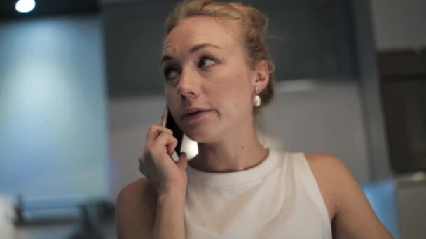 Közelkép kézifegyver egy szőke nőről, aki telefonon beszél. — Stock videók
