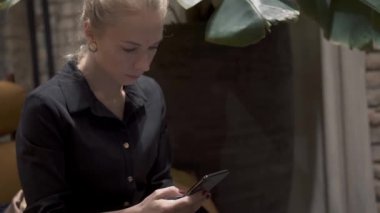 Sarışın bir kadının telefon tutarken, yazarken orta pozu.
