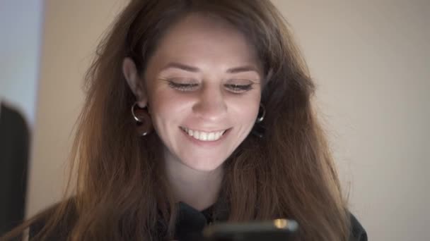 Primer plano de cabello castaño femenino feliz con un teléfono, sonriendo — Vídeos de Stock