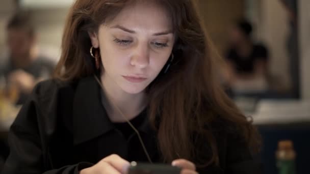 Close up of female brown hair scrolling a phone in a restaurant — 图库视频影像