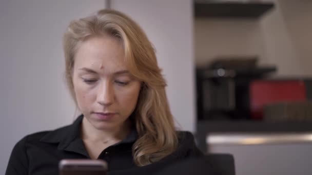 Kézi felvétel egy szőke nőről, amint SMS-ezik a telefonban. — Stock videók