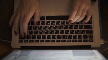 Close up above shot of female hands with laptop typing at night