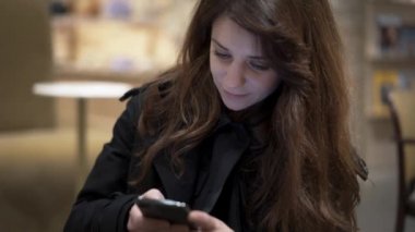 Close up of female brown hair scrolling a phone, smiling