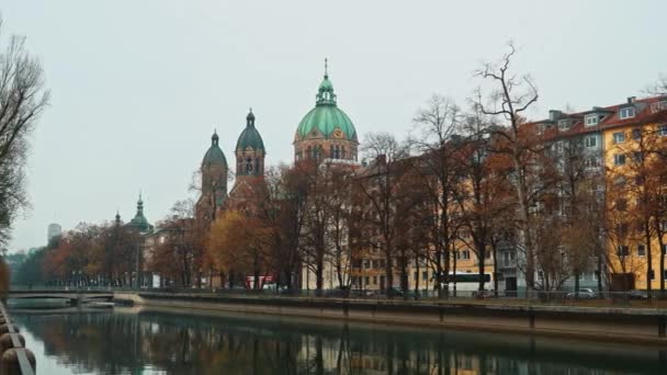 MUNICH - 22 DE NOVIEMBRE: Panorama de izquierda a derecha en tiempo real que establece la toma de la Iglesia de San Lucas, ubicada a orillas del río Isar en un día de otoño, 22 de noviembre de 2018 en Munich . — Vídeo de stock