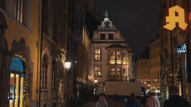 MUNICH - NOVEMBER 22: Locked down real time shot of a beautiful building in the evening in the German city of Munich. People walk around the evening city, November 22, 2018 in Munich. — Αρχείο Βίντεο