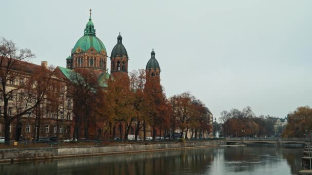 Locked down real time shot of the Church of St. Luke, located on the banks of the river Isar on an autumn day. — Stockvideo