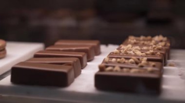 Zoom out of several chocolate small cakes behind the glass