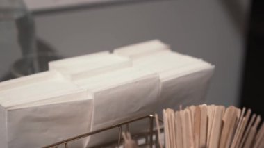 Tilt down shot of white napkins and wooden sticks in a cafe