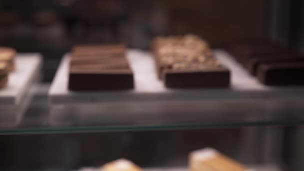 Zoom in of several chocolate small cakes behind the glass — Stok video