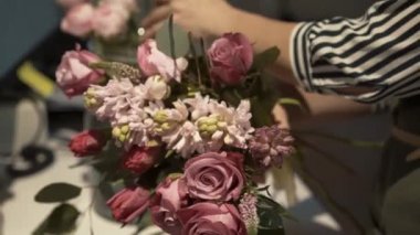 Kadın çiçekçinin yakın çekimleri pembe çiçeklerden bir buket yapıyor