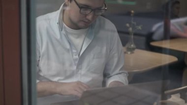 Bir adamın bir kafede dizüstü bilgisayarda oturuşunu çek.