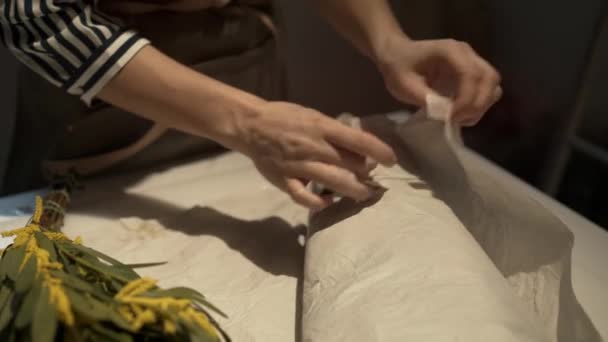 Close-up van vrouwelijke handen bloemist ontvouwen mimosa — Stockvideo