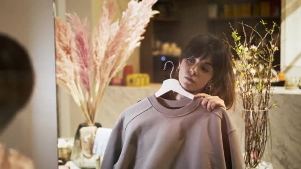 Fiatal nő gazdaság próbál rózsaszín szürke pulóver — Stock videók