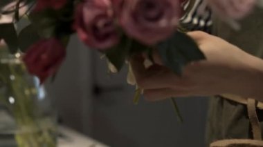 Kadın çiçekçinin yakın çekimleri pembe çiçeklerden bir buket yapıyor