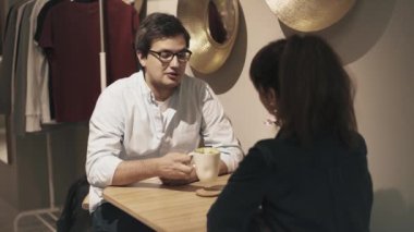 Bir kafede kahve içen, kadın ve erkek arasında geçen bir fotoğraf.