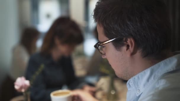 Handheld shot of man and woman drinking coffee indoors — Stock video