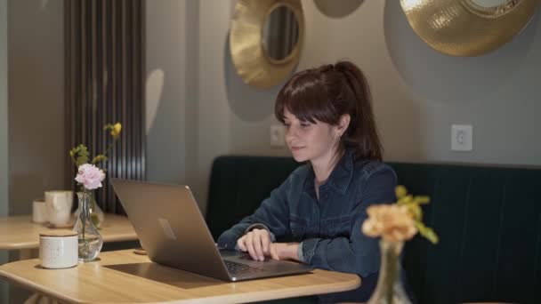 Midden schot van vrouw werken met een laptop in een coffeeshop — Stockvideo