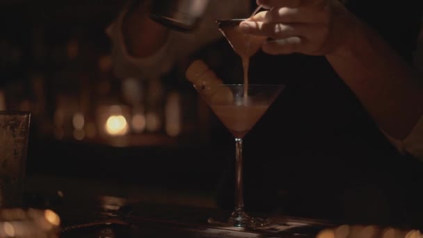 У реальному часі постріл бармена виливає коктейль у склянку. Бармен готує коктейлі в барі в Бангкоку (Таїланд).. — стокове відео