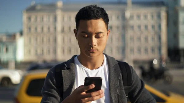 Портрет молодого азіата, який дивиться на телефон у Москві. Турист у Москві. Концепція свободи. — стокове фото