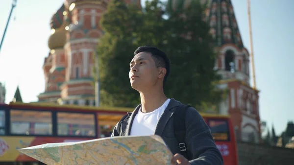 Retrato de um jovem asiático a olhar para o mapa. A Catedral de Vasily o Abençoado no fundo, Moscou Rússia. Área da Praça Vermelha . — Fotografia de Stock