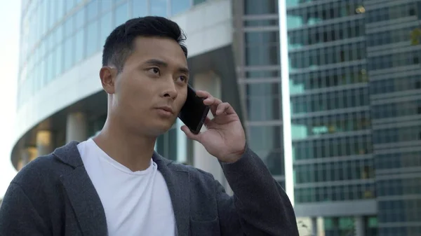 Retrato de jovem empresário asiático falando ao telefone no centro da cidade. Moscou distrito de negócios internacional, a chamada cidade de Moscou — Fotografia de Stock