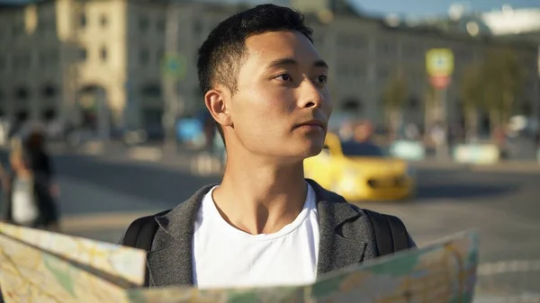 Zijaanzicht portretfoto van een jonge Aziatische man die naar een kaart kijkt. Toerist in Moskou. Moskou is de hoofdstad van Rusland. — Stockfoto