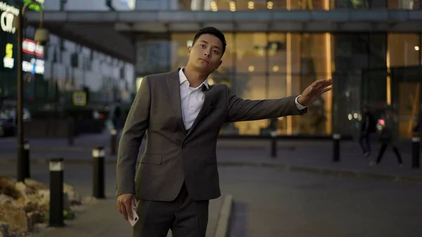 Genç Asyalı işadamı, şehir merkezindeki iş toplantısına gitmek için taksiye biniyor. Akşam vakti.. — Stok fotoğraf