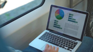 Tanınmayan bir işadamı trene binerken grafikler ve istatistikler üzerinde çalışıyor. İş hayatı anlayışı. 