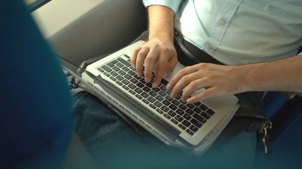 Vue de dessus d'un homme d'affaires méconnaissable mains en utilisant son ordinateur portable pendant qu'il est en train . — Photo