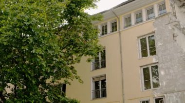 MUNİK, Almanya - 25 HAZİRAN 2019: Ağaç dallarının Pan çekimi ve yıkılan bina