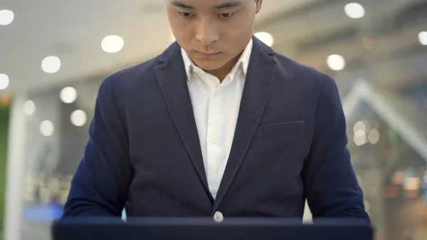 Frente vista de ásia masculino empresário em terno trabalhando com laptop em seus joelhos — Fotografia de Stock