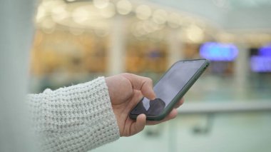 Adamın eli bulanık sarı arka planda bir telefonu kaydırıyor.