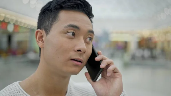 Close-up van aziatische man praten op telefoon op winkelcentrum achtergrond — Stockfoto