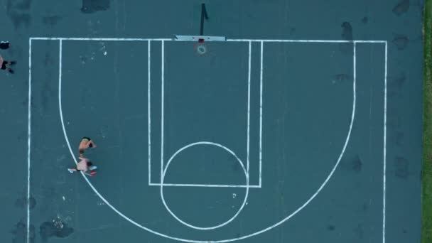 Drone tiro superior de dos hombres enérgicos jugando al baloncesto al aire libre — Vídeo de stock