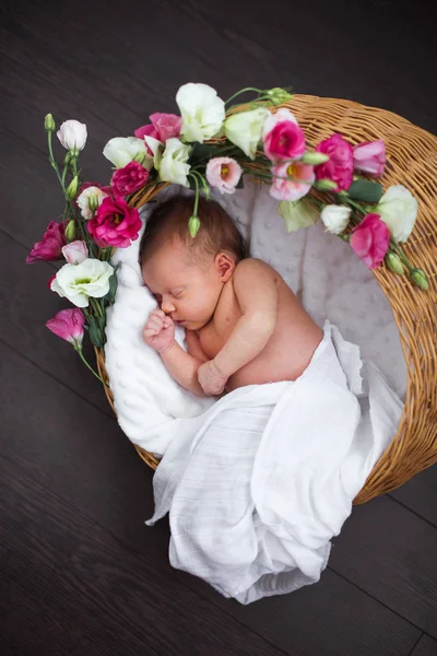 Nyfödda barn sover i korgen med blommor — Stockfoto
