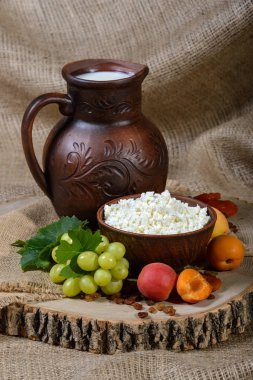 Ülke stil. Süzme peynir bir kil çanağı, üzüm, kayısı ahşap arka plan üzerinde.