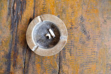 Sigara araya eski ahşap bir masa üzerinde bir kül tablası.