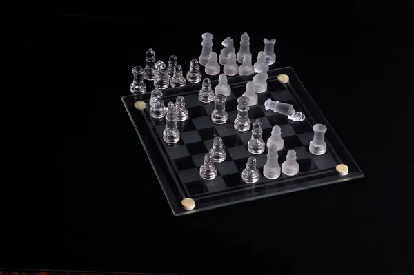 Glass chess set with dark background.