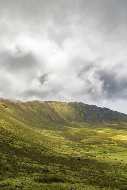 Portekiz, Azores 'deki Corvo adasındaki Corvo Krateri' nin kenarından kara bulutlar hızla geçer..