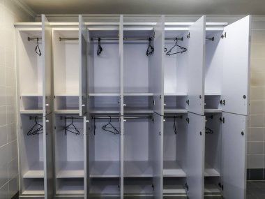 Kapısı açık beyaz plastik bir dolap ve otel tuvaletinde elbise askısı.