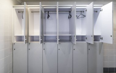 Kapısı açık beyaz plastik bir dolap ve otel tuvaletinde elbise askısı.