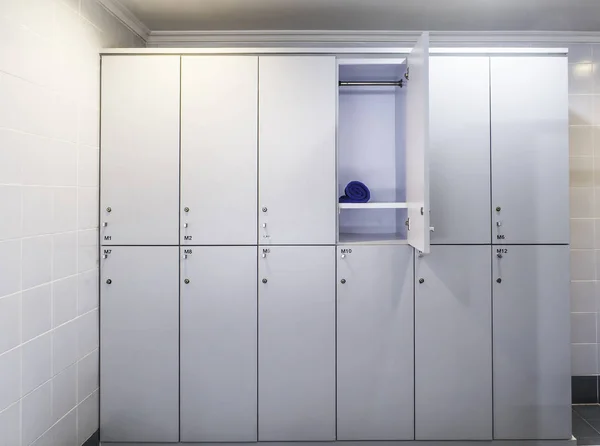 浴室宾馆装有一扇门的一套白色塑料储物柜和蓝色毛巾 — 图库照片