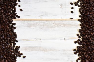 Kavrulmuş kahve çekirdekleri beyaz yıkanmış ahşap zemin üzerinde bir üstten görünüm görüntüsü. 