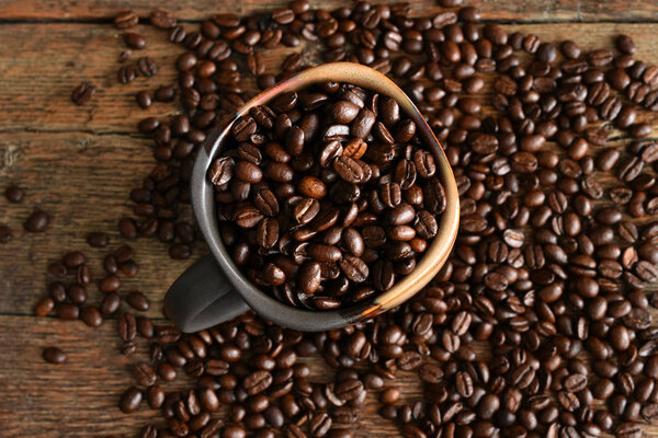 A top view image of roasted coffee beans in a ceramic coffee cup. 