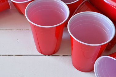Kırmızı plastik bardak beyaz piknik masa üzerinde içme görüntüsünü yakından. 
