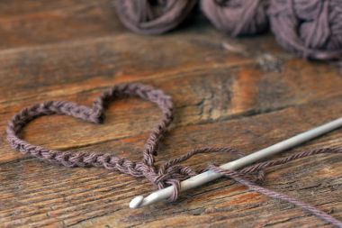 Tığ işi kalp simgesi ve tığ eski ahşap masa görüntü yakından. 