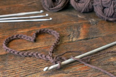 Tığ işi kalp simgesi ve tığ eski ahşap masa görüntü yakından. 