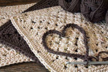 Kahverengi ve bej tığ işi dishcloths üstüne bir tığ işi kalp simgesi. 